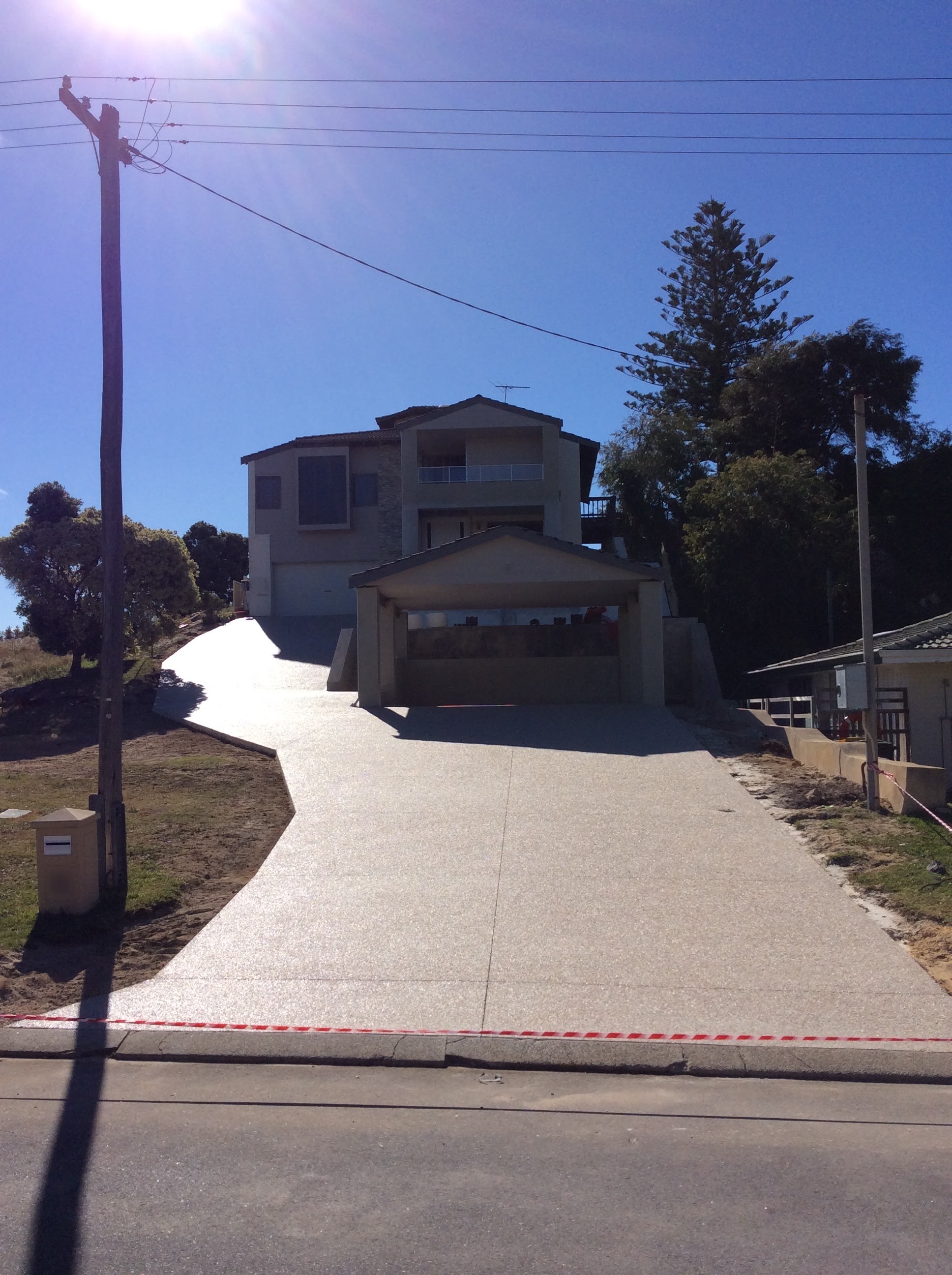 Sloped exposed aggregate driveway leading up to a two-storey home