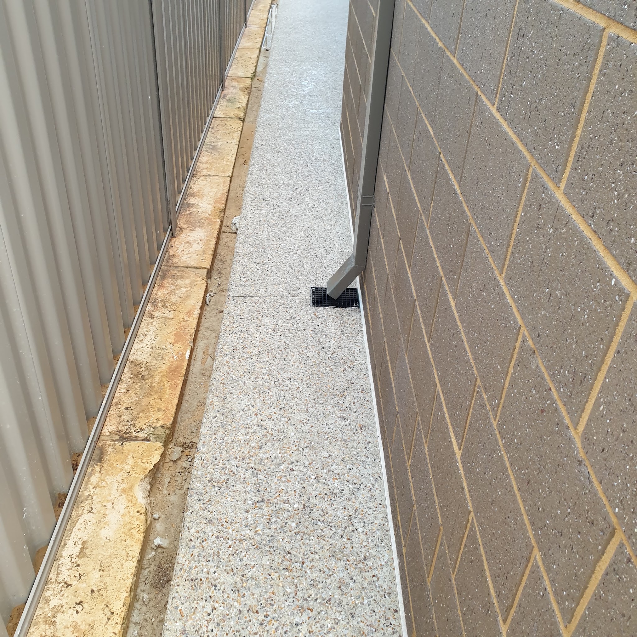 Exposed aggregate path running down the side of a brick house