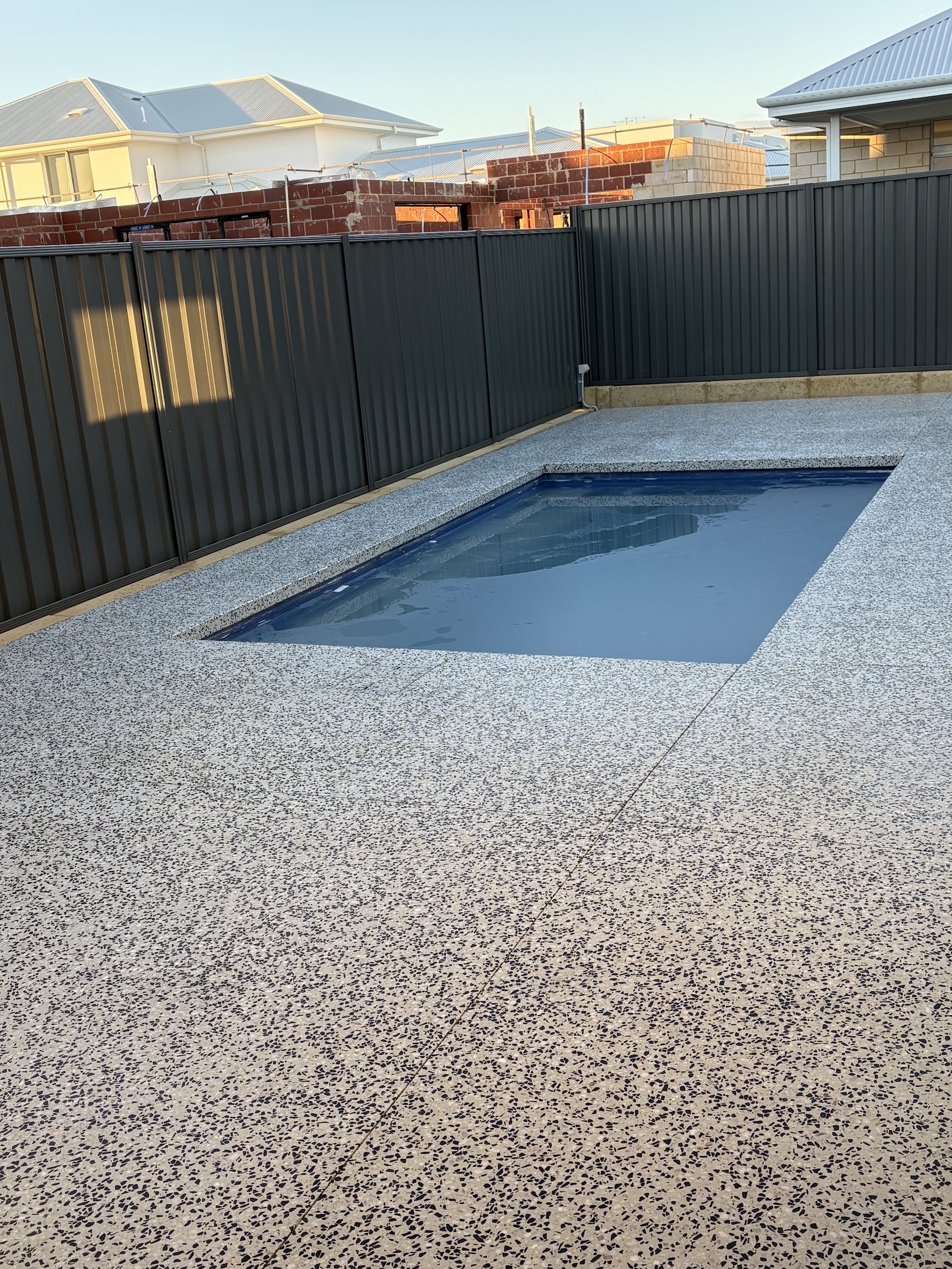 Pool surround in exposed aggregate running to the fence